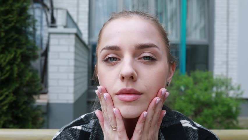 Young Woman Applying Skincare Products Outdoors in a City Setting