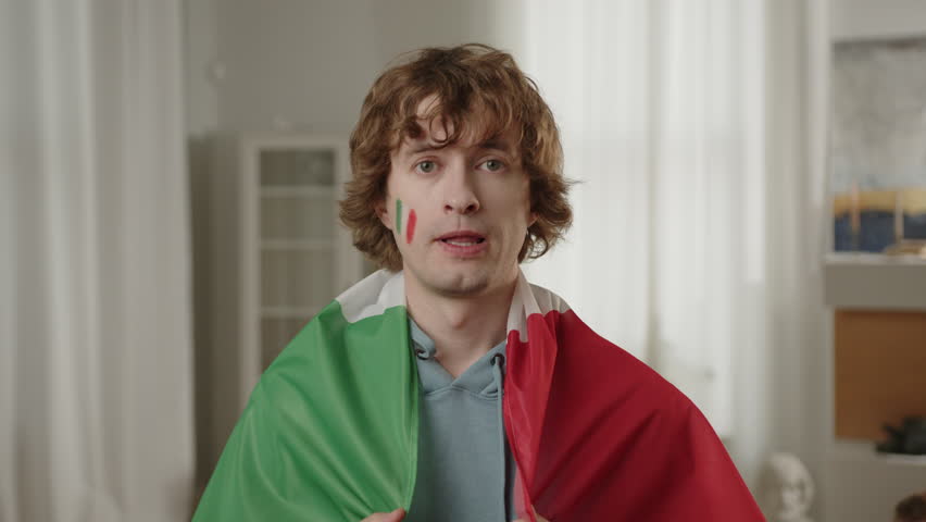 Italian Sport, football fan cheering for favorite Italy team, with painted flag on cheeks. World Sport games. Football, sports and soccer fans. Smiling and cheering, Paris Games, Slow Motion