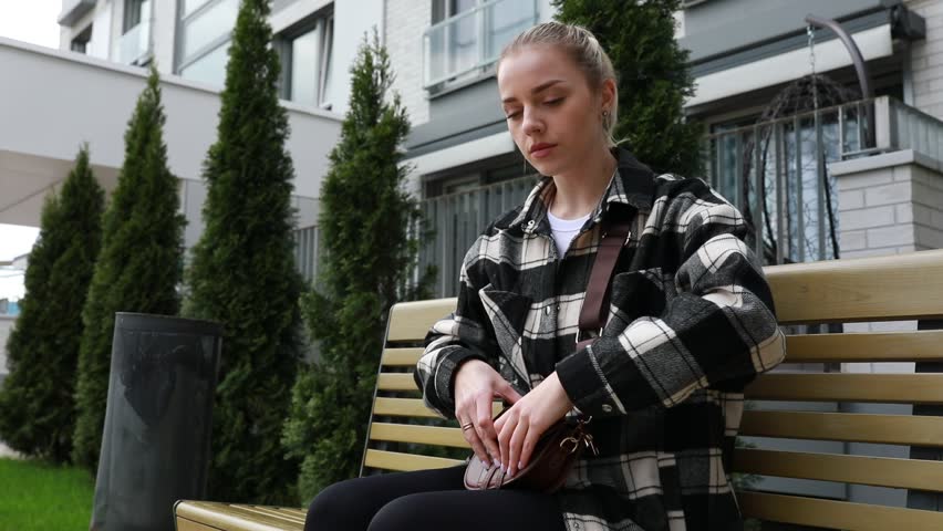 Young Woman Sitting Alone on a Park Bench During a Cloudy Afternoon