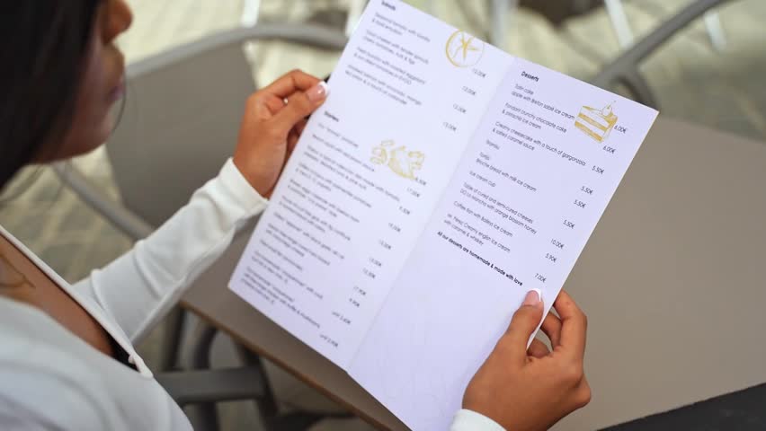 Close-up hands of Elegant Woman Hold Menu Restaurant Choosing Dish or Beverage Lunch City Break. Eating in Public Places Cafeteria. Ordering for waiter. Slim Woman Diet Catering Alcohol Drink Dish.