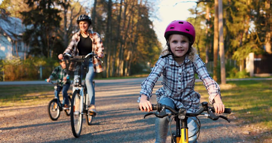 happy young girl cycling together with family. bike ride