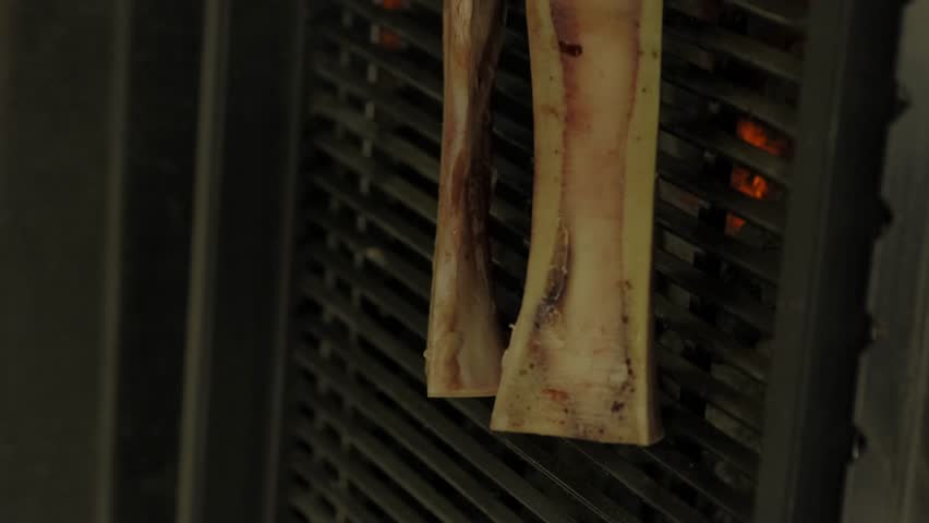 The process of cooking bone marrow on a grill over an open fire. Chef cooking on grill, close up, vertical video Royalty-Free Stock Footage #3491145479