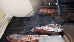 Watch the video of grilling steaks on a gas grill for a delicious cooking experience. Ribeye or pork steaks are prepared with tongs, showcasing the art of grilling cuisine