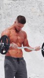 Male bodybuilder doing barbell biceps exercises. Workout in nature. Vertical video.