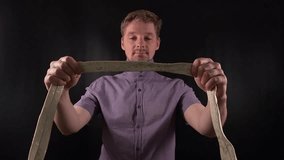 Dapper portrait of a stylish young man adjusting a crisp white necktie. Clad in a vibrant purple shirt with casual stubble he exudes an effortlessly cool yet refined vibe on the minimal black backdrop - Powered by Shutterstock - Get 15% off with code: PIKWIZARD15