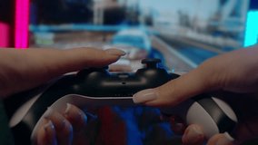 Gamer girl is playing a racing video game on a console using a joystick. Close-up of her manicured hands illuminated by neon lights. Close up. 4k