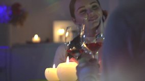 Romantic dinner. Young couple Toasting Wine Glass In restaurant or at home. Dating. Beautiful brunette woman on romantic dinner drinking at bar. Date. Valentine's Day celebrating. 4K UHD Slow motion