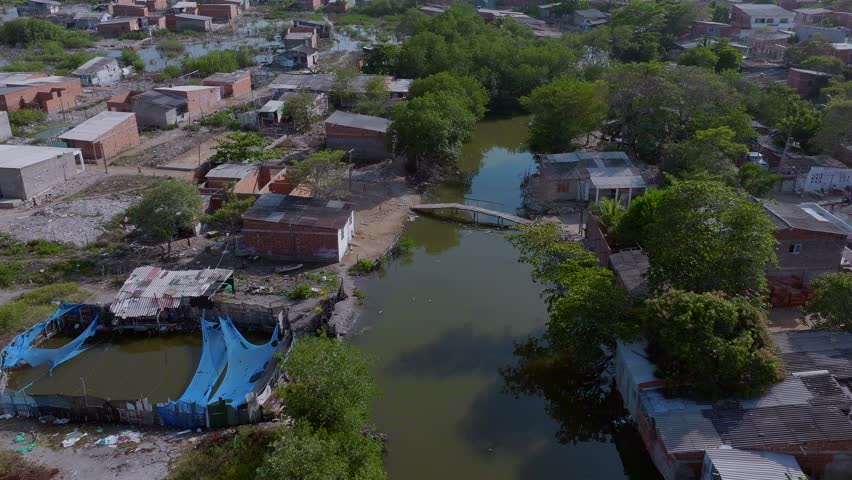 Aerial drone shot over poor neighborhood in Cartagena and a child crosses the bridge