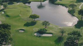 A pond, sand traps, and trees casting long shadows sit on a green golf course in Florida on a sunny afternoon - Powered by Shutterstock - Get 15% off with code: PIKWIZARD15