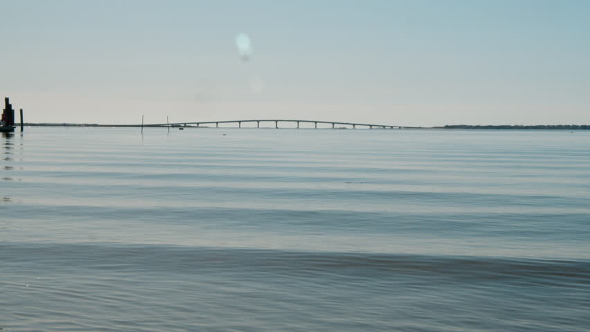 Glassy Waves Roll under Distant Bridge on Skyline