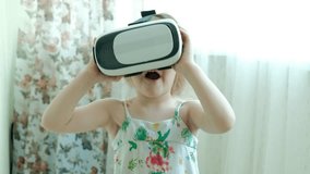 Little girl in white shirt watching 360 video at home, wearing VR headset. 4k