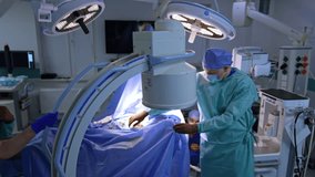 C-Arm x-ray machine is set over the patient covered with blue sheet at operation. Medic arrange the equipment in surgical room. - Powered by Shutterstock - Get 15% off with code: PIKWIZARD15