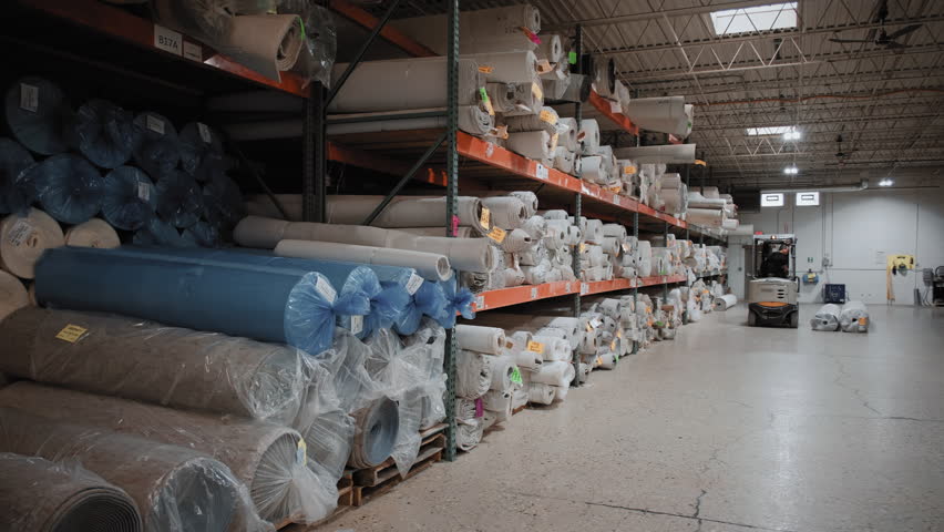 Piles of new rolls of carpet in a store warehouse. Carpet rolls stacked at store. Wide shot