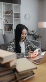 Vertical video of young asian woman student or freelancer relaxing at home typing browsing products in internet online store reading news or social media on smartphone while take a break indoors	