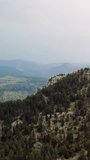 Drone footage captures mountain, forest towering skyward. Aerial view shows mountain, forest in majestic display. Video highlights mountain, forest surrounded by dense greenery