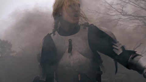 Wounded woman warrior in medieval armor wanders through the smoke