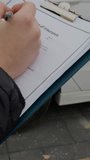 Person fills out paperwork for automobile insurance vertical video. Car insurance underscores importance of financial protection in face of potential damages accidents offering peace of mind.