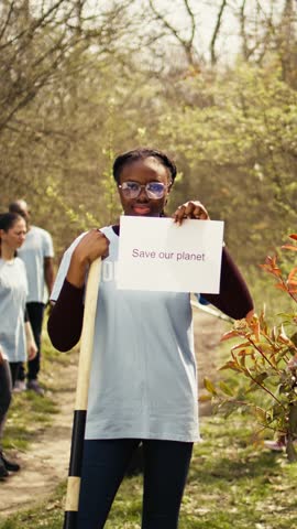 Portrait of african american activist holding poster with save our planet message, spread environmental care and awareness. Young woman posing with banner to fight ecological justice. Camera B. Royalty-Free Stock Footage #3491642907