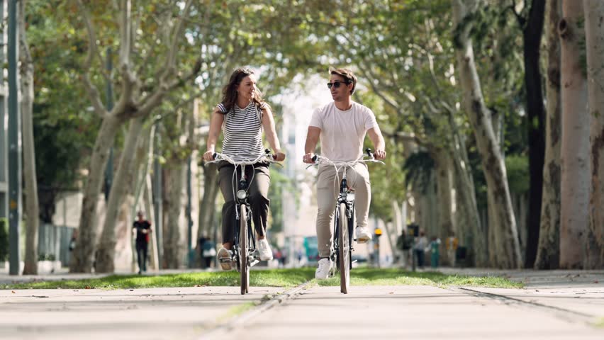 Video of of happy loving couple cycling while looking each other in the city