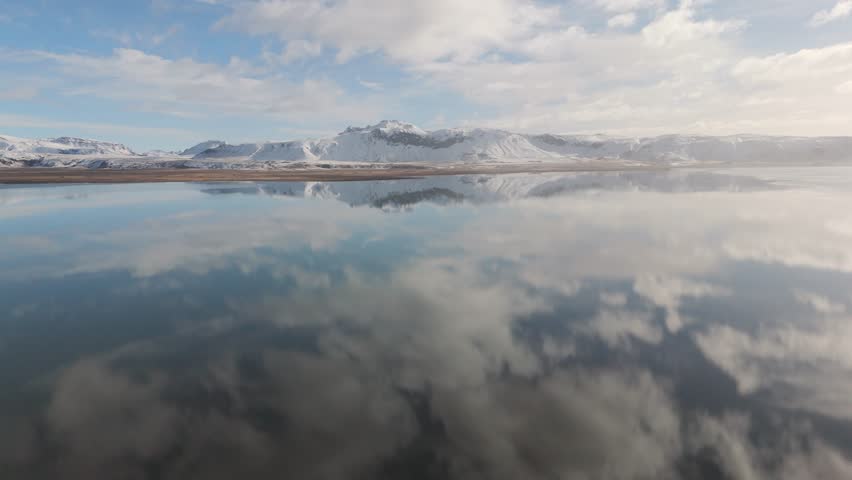 Blue water reflecting sky white clouds in Icelandic volcanic environment Aerial
