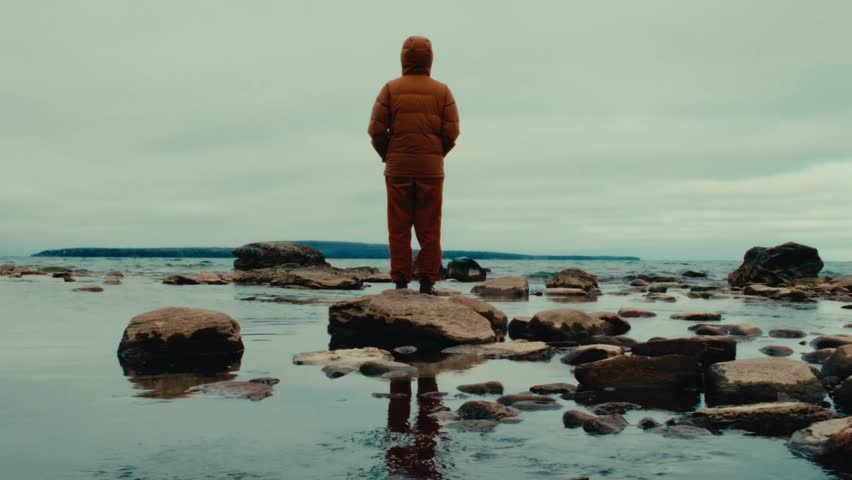 Standing solitary on a rocky outcrop, a lone figure gazes into the distance, the vastness of nature, the essence of self-reflection and introspection found Royalty-Free Stock Footage #3491670155