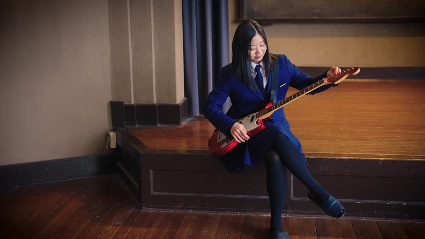 Japanese High School Girl Tunes Guitar for Band Practice