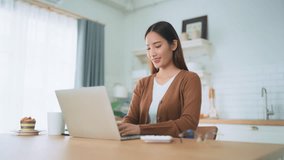 Beautiful young Asian woman working with laptop computer in home kitchen. Work at home - Powered by Shutterstock - Get 15% off with code: PIKWIZARD15