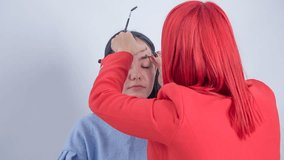 A make up artist shapes the model's eyebrows during the make up session.