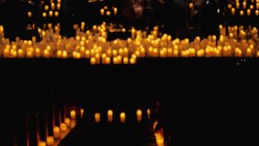 A serene scene of an orchestra playing by candlelight. The warm glow from candles illuminates performers and their instruments, creating a tranquil and romantic concert atmosphere. Blurred video