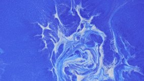 Fluid art footage with light blue and white overlapping colors. A closeup of swirling shine paint, with fluid patterns resembling an abstract painting. Abstract textures with sparkling sparkles.