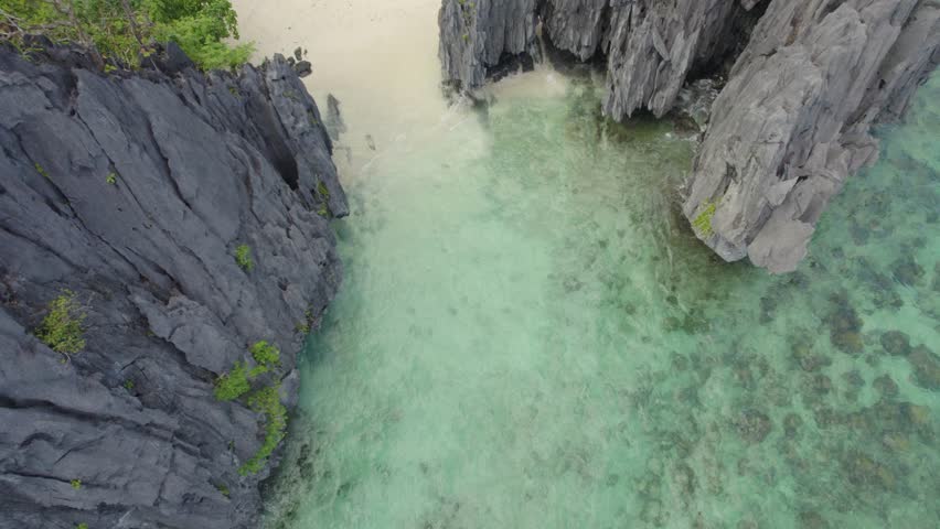 A beautiful view of a beach with a small island in the distance. The water is calm and the sky is clear. Aerial view of the amazing Big Lagoon in El Nido, Palawan, Philippines Royalty-Free Stock Footage #3491880931