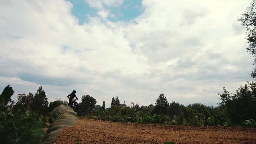 A off road moto cross type motor bike, in mid air during a jump with a dirt trail. High quality 4k footage