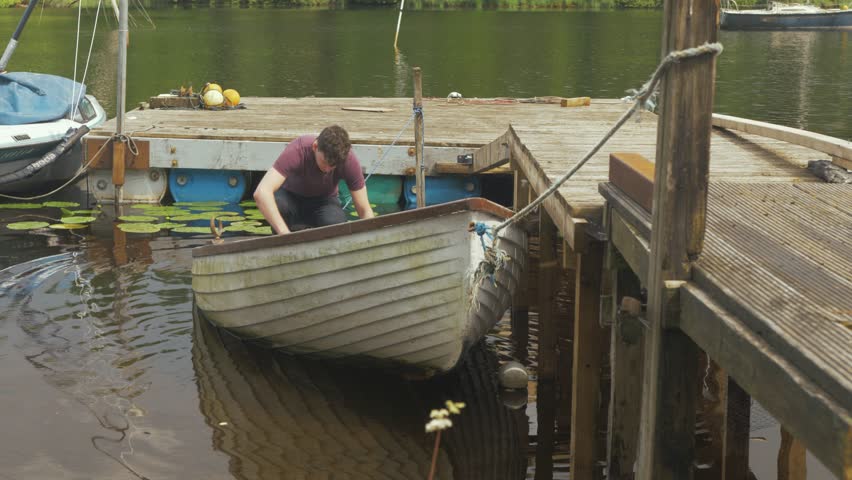 A young man bailing out rainwater from fishing boat