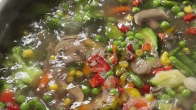 Soup of vegetable mix and mushrooms slices during its cooking in pot on a stove, top view 
 - Powered by Shutterstock - Get 15% off with code: PIKWIZARD15