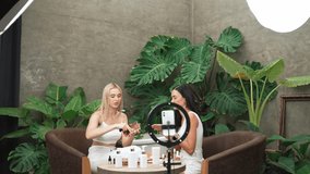 Two beautiful content creator making natural beauty and cosmetic tutorial on green plant leave garden video. Beauty blogger showing how to apply beauty care to social medial audience. Blithe