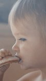 A video capturing a young child as they eat a piece of food. Vertical footage.
