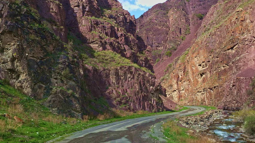 Driving off road rock mountain in gorge of Dzhartash river in Kyrgyzstan at sunny spring day. Off road sport and recreation. Geologic landscape of central Kyrgyzstan.