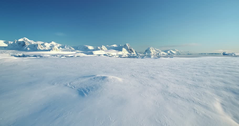 Winer snow covered Antarctica aerial landscape. Frozen ocean and towering mountain range under blue clear sky, sunny wild nature scene. Sea polar coast hill. Antarctic travel exploration background