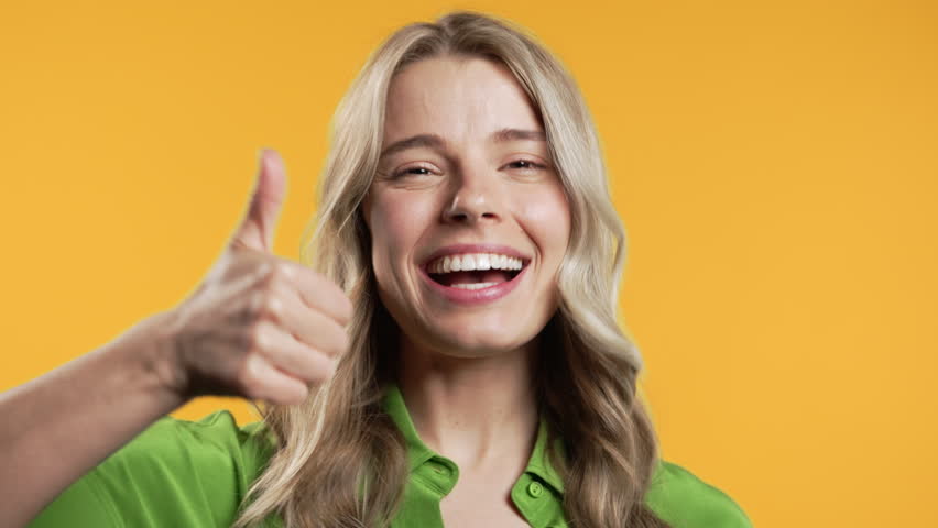 Positive woman with hand sign like, thumbs up gesture. Lady on yellow background