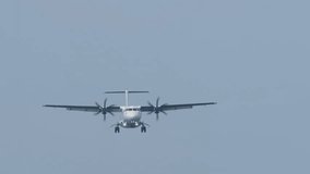 Front view of a turboprop airplane with an unrecognizable livery flying, descending for landing. Twin-engine short-haul regional passenger aircraft. Blue background. - Powered by Shutterstock - Get 15% off with code: PIKWIZARD15