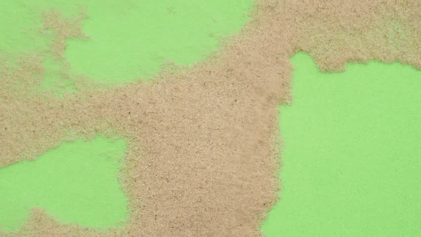 Closeup abstract sand transition blowing over green screen chroma key background