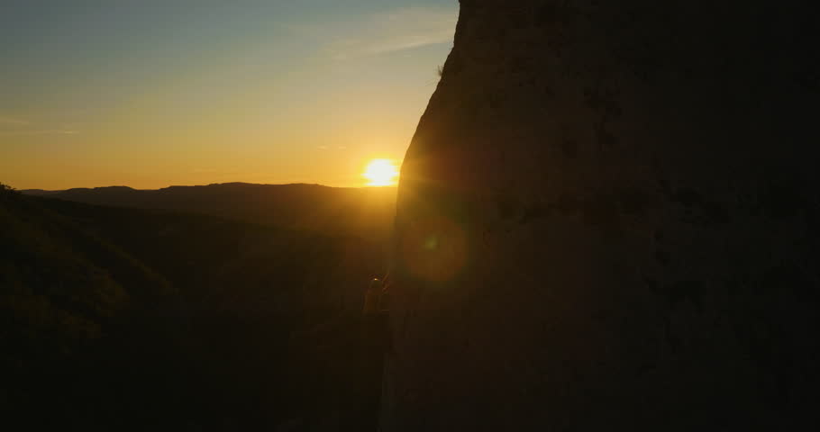Aerial of a man silhouette climbing up the wall at amazing sunset. Royalty-Free Stock Footage #34926589