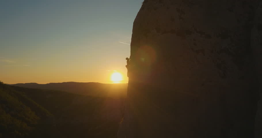 Aerial fly-by a man rock climbing outdoors at amazing sunset. Royalty-Free Stock Footage #34926604
