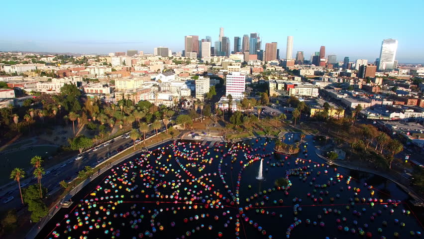Aerial Shot Of Modern Buildings By Famous Macarthur Park Against Clear Sky, Drone Flying Backwards On Sunny Day - Los Angeles, California