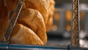 vertical video close-up of freshly baked warm bread on an iron rack in professional kitchen