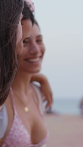 Vertical. Group of beautiful young attractive female friends walking embracing happy on beach. Laughing Caucasian girls enjoying vacation outdoors. People having fun on vacation in Mediterranean. 