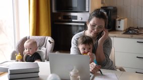 Happy family concept. Mom at home with baby in isolation works online on a laptop. online calls. mother with children works online on laptop. mother makes a phone call with the baby sitting on her lap - Powered by Shutterstock - Get 15% off with code: PIKWIZARD15