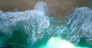 Big waves of tropical emerald colored sea breaking on sandy beach. Aerial top-down view