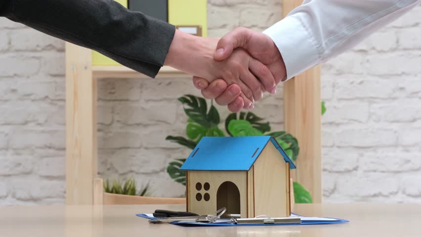 Real estate agent shaking hands with buyer after signing contract. People closing deal with handshake. Mortgage, home loan, insurance and buy property concept