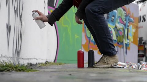 Juvenile delinquent, using spray paint to create graffiti on a concrete wall